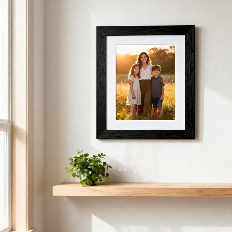 Framed family photo on a wall next to a window with a plant on a shelf.