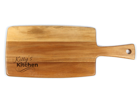 A beige wooden cheese board with 'Kitty's Kitchen' engraved on it, featuring a handle on the right side.