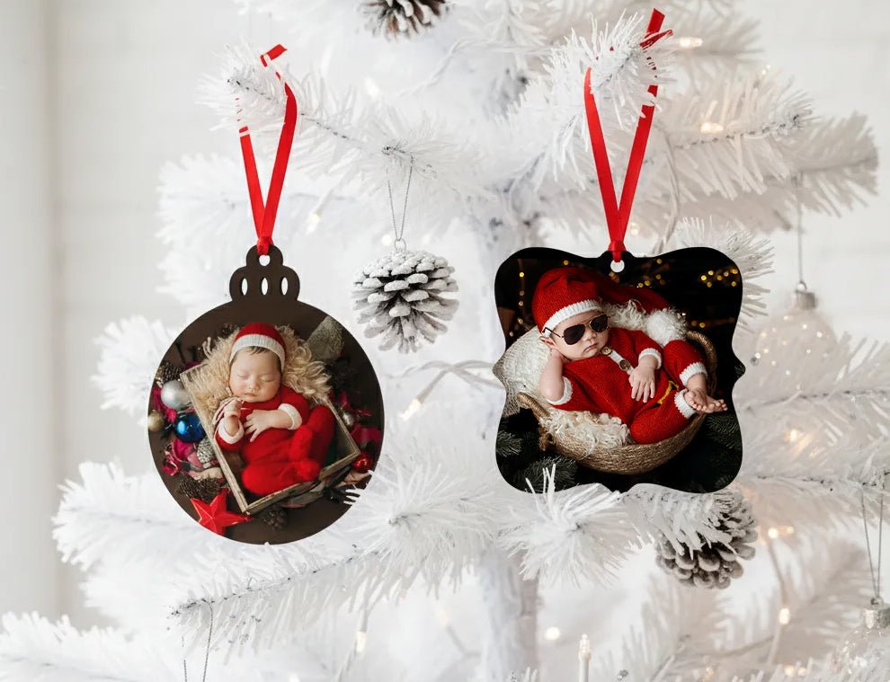 Two Metal Christmas tree ornaments personalised with photos of children in Santa hats on a white tree.